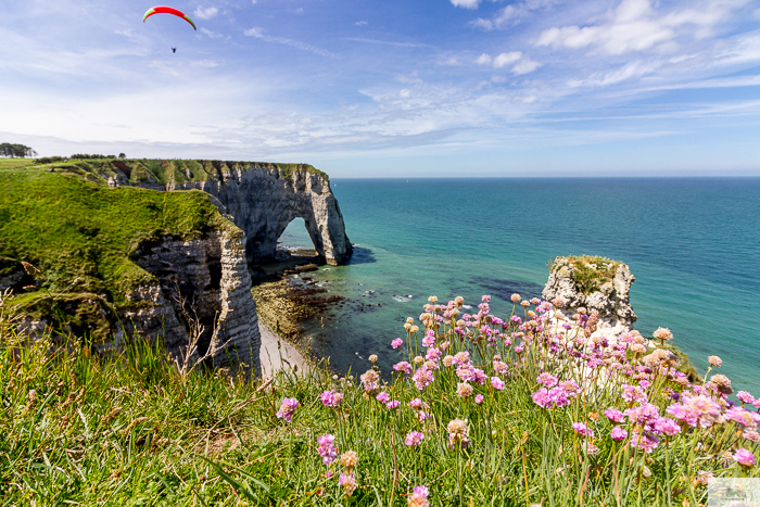 a paraglider fying over the cliffs in Etretat