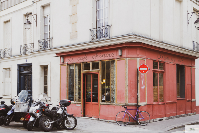 Motor vehicles parked next to a purple bike on the corner of a cafe in France