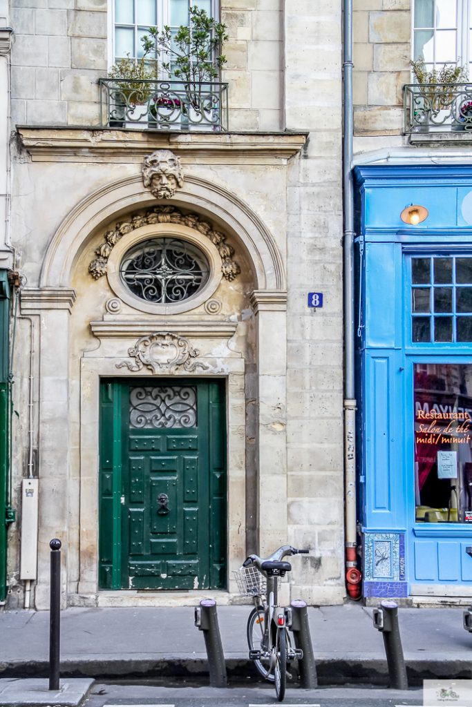 Tight shot photos of building with green door next door to blue building in France 