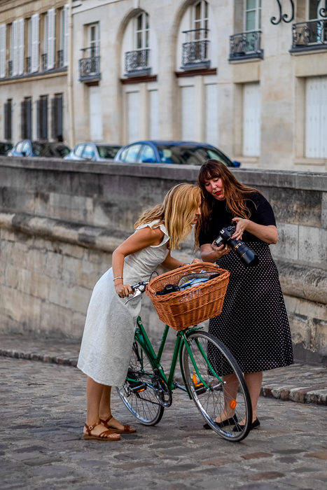 Krystal Kenney showing Julia a photo while Julia rests against bike