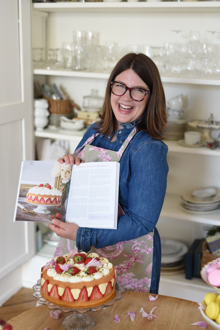 Molly Wilkinson, Pastry Chef, holding her book in kitchen