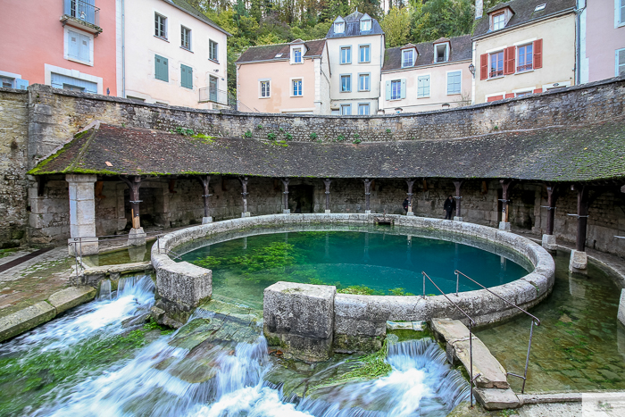 Flowing water of the Fosse Dionne, which sits right in the middle of a narrow residential street that encircles it.